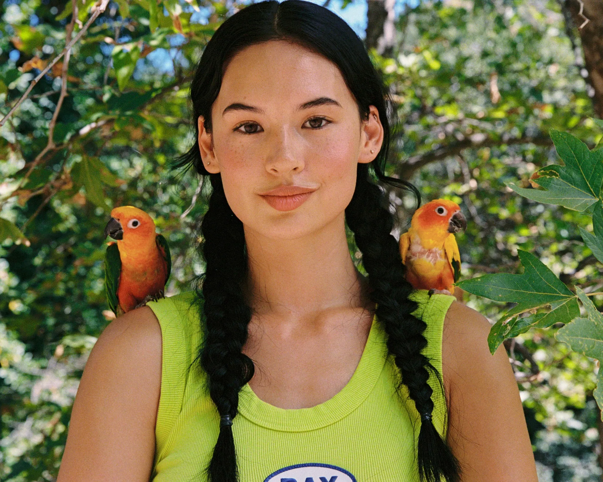 A model in neon green with two parrots on her shoulders, shot on 35mm